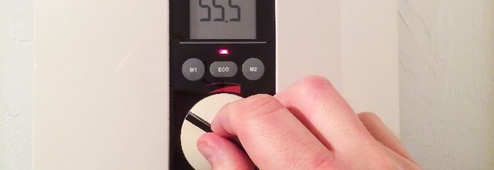 Hand stellt Temperaturregler ein